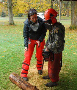 Meg Carter demonstrates proper chainsaw handling techniques to a student.